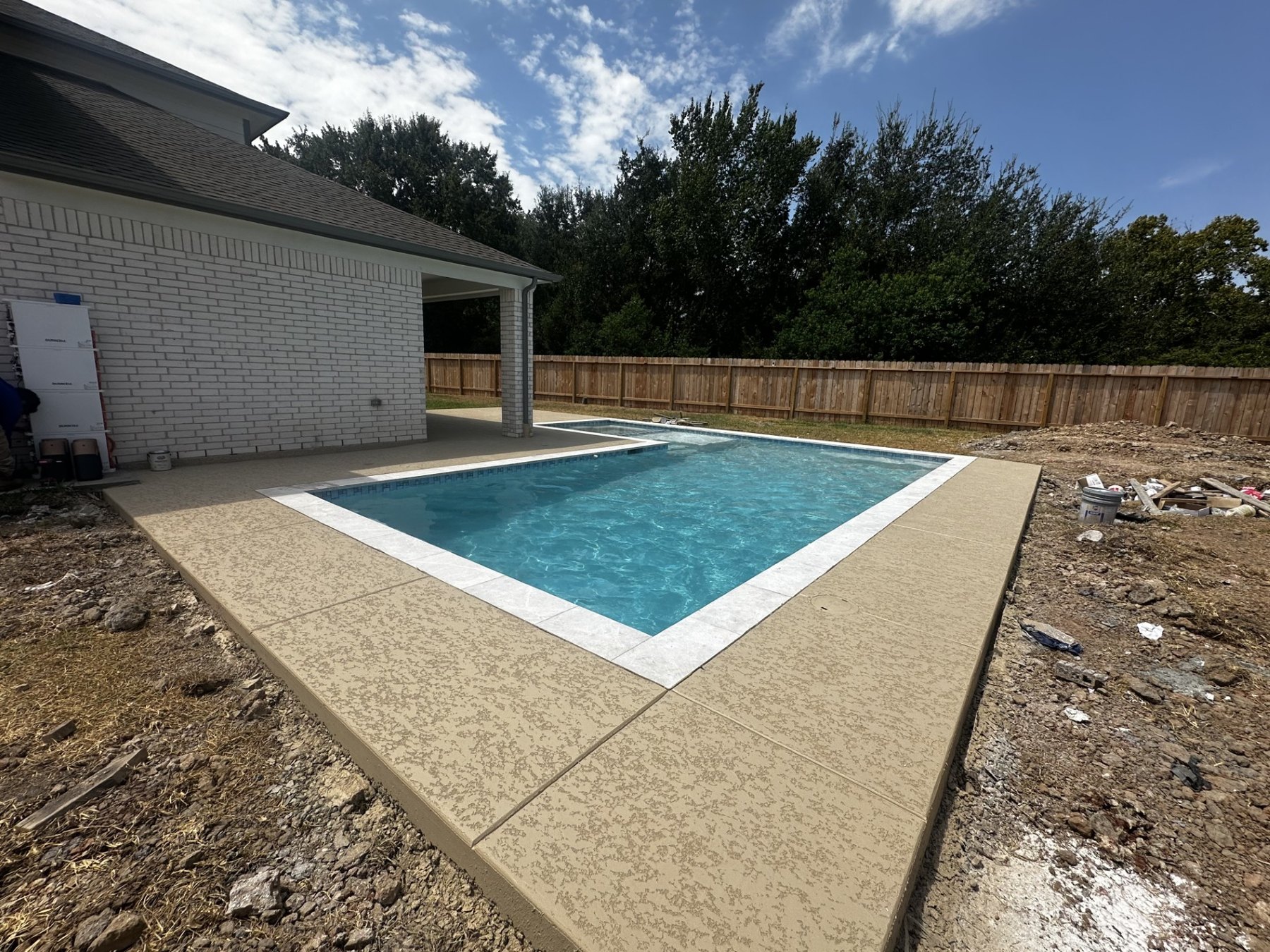 Rectangular swimming pool with light coping, textured deck, and raised spa viewed from the corner